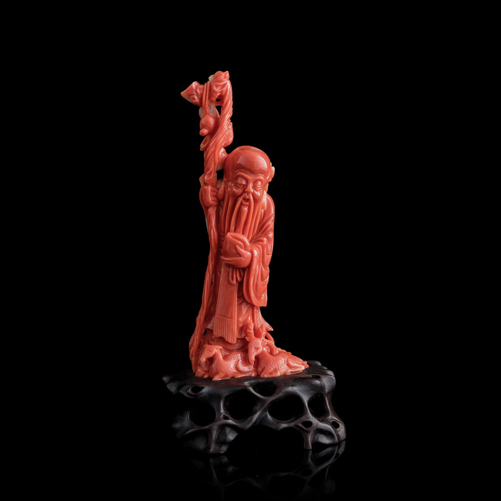 A Chinese carved coral figure of Shouxing, 19th century: A Chinese carved coral figure of Shouxing 19th century Shouxing is holding an oversized peach in one hand and a wooden staff in another, representing immortality and the dignity of old age; with attac