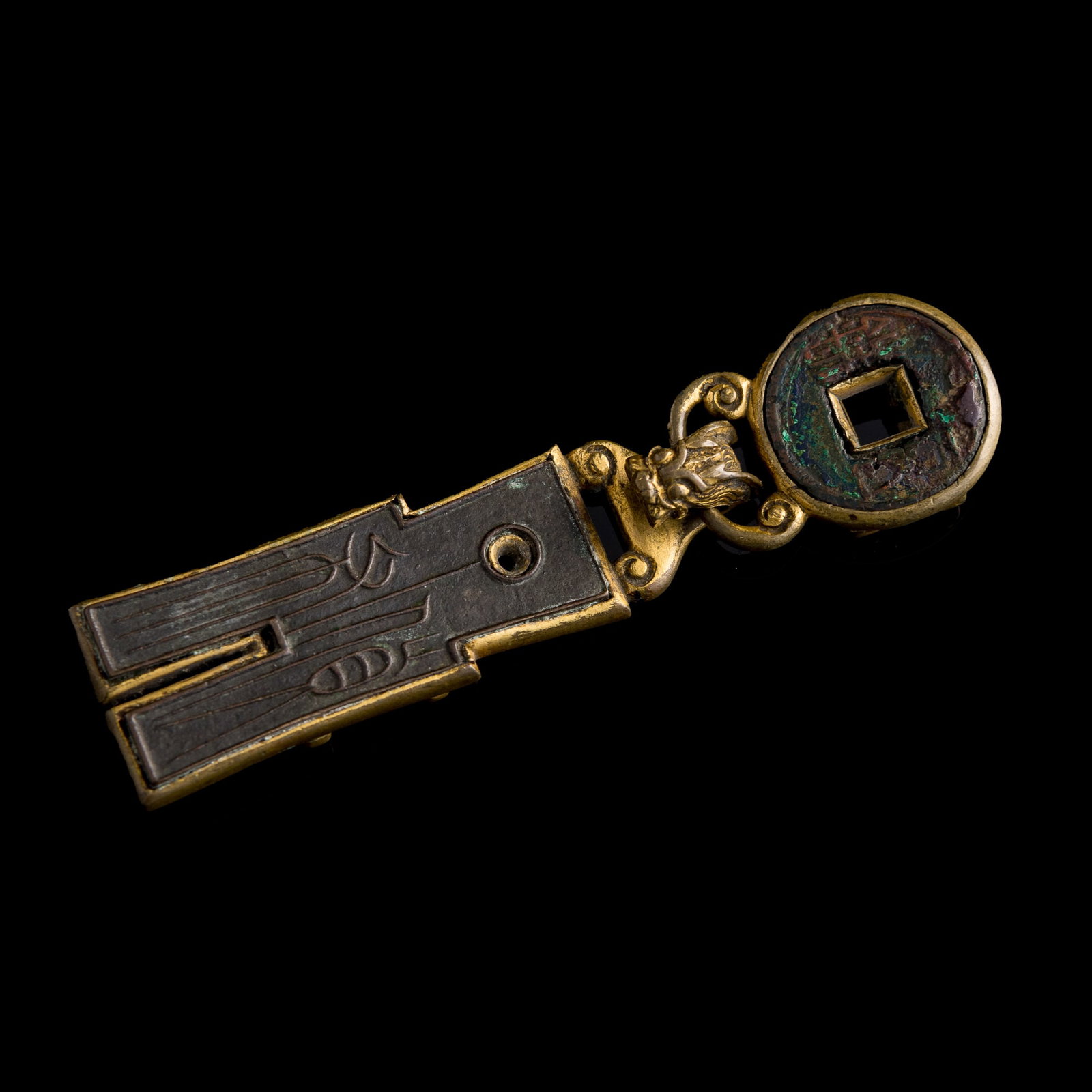 A Chinese gilt-copper belt buckle inset with an ancient coin, 18th century: A Chinese gilt-copper belt buckle inset with an ancient coin 18th century H: 1 1/8, W: 4 1/4, D: 1/2 in. (H: 2.9, W: 10.8, D: 1.3 cm.) Weight: 69.9 g Private collection, Calgary, Canada.