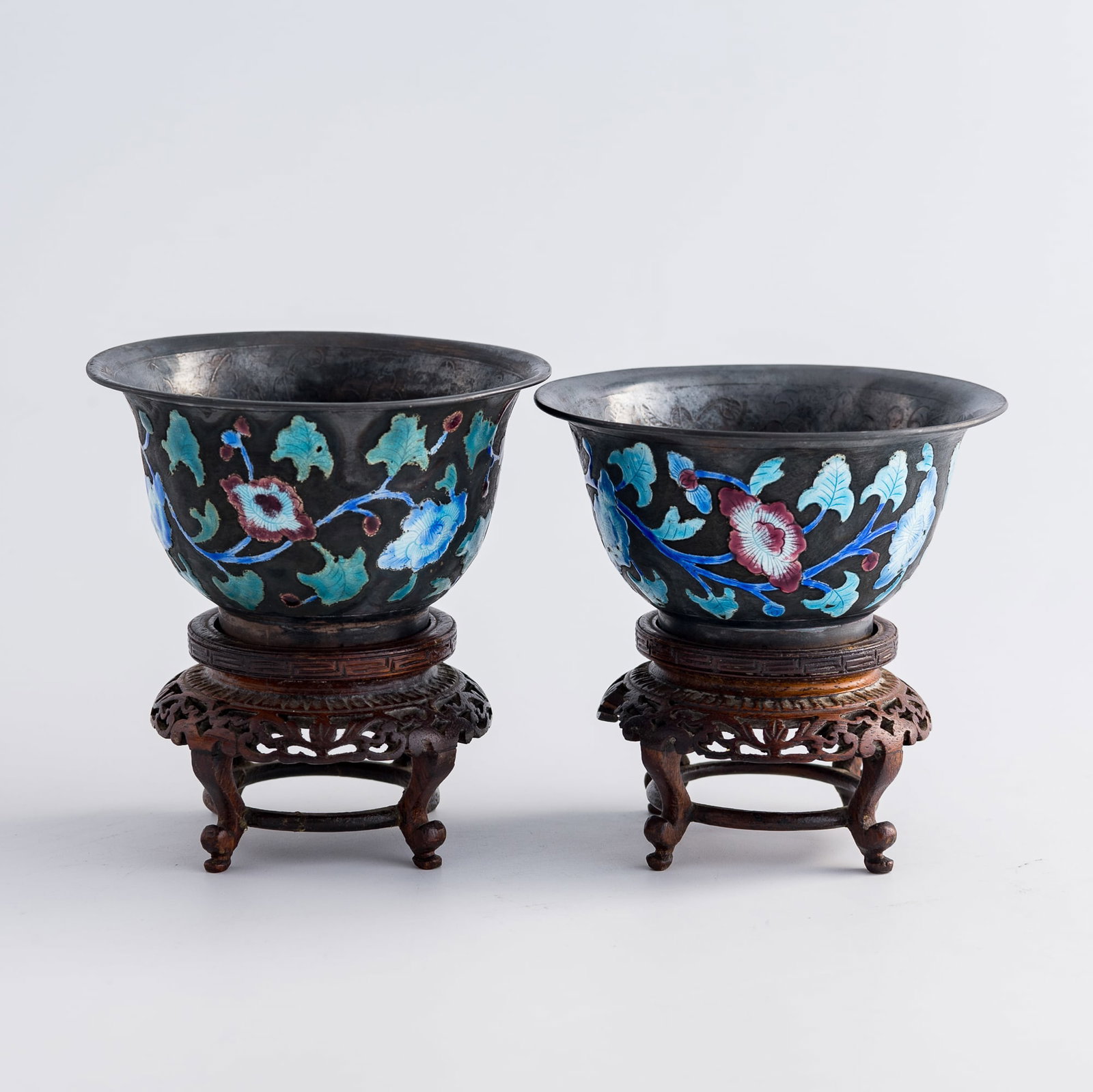 Two Chinese silver enamel floral cups, 19th century: Two Chinese silver enamel floral cups 19th century One with nine-character mark to underside, other with two-character mark and 'CHINA' and 'SILVER' marks to underside; each sold with hardwood stand. 