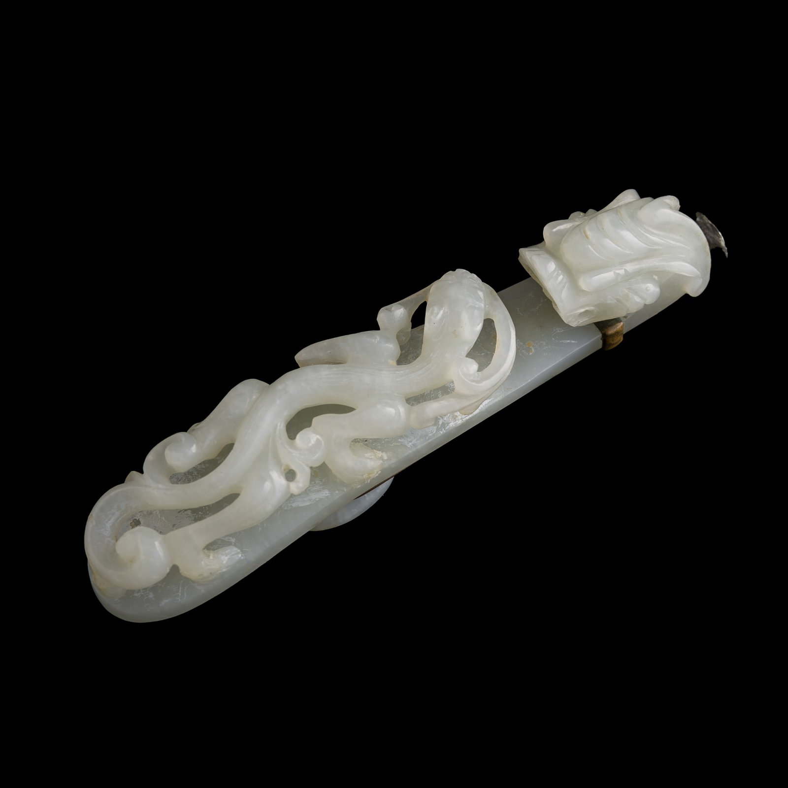 A Chinese white jade dragon hook, Qing dynasty: A Chinese white jade dragon hook Qing dynasty With a metal fitting affixed to the reverse of the dragon hook. H: 1 1/4, W: 1, D: 5 1/4 in. (H: 3.2, W: 2.5, D: 13.3 cm.) Private collection, Mount Laure