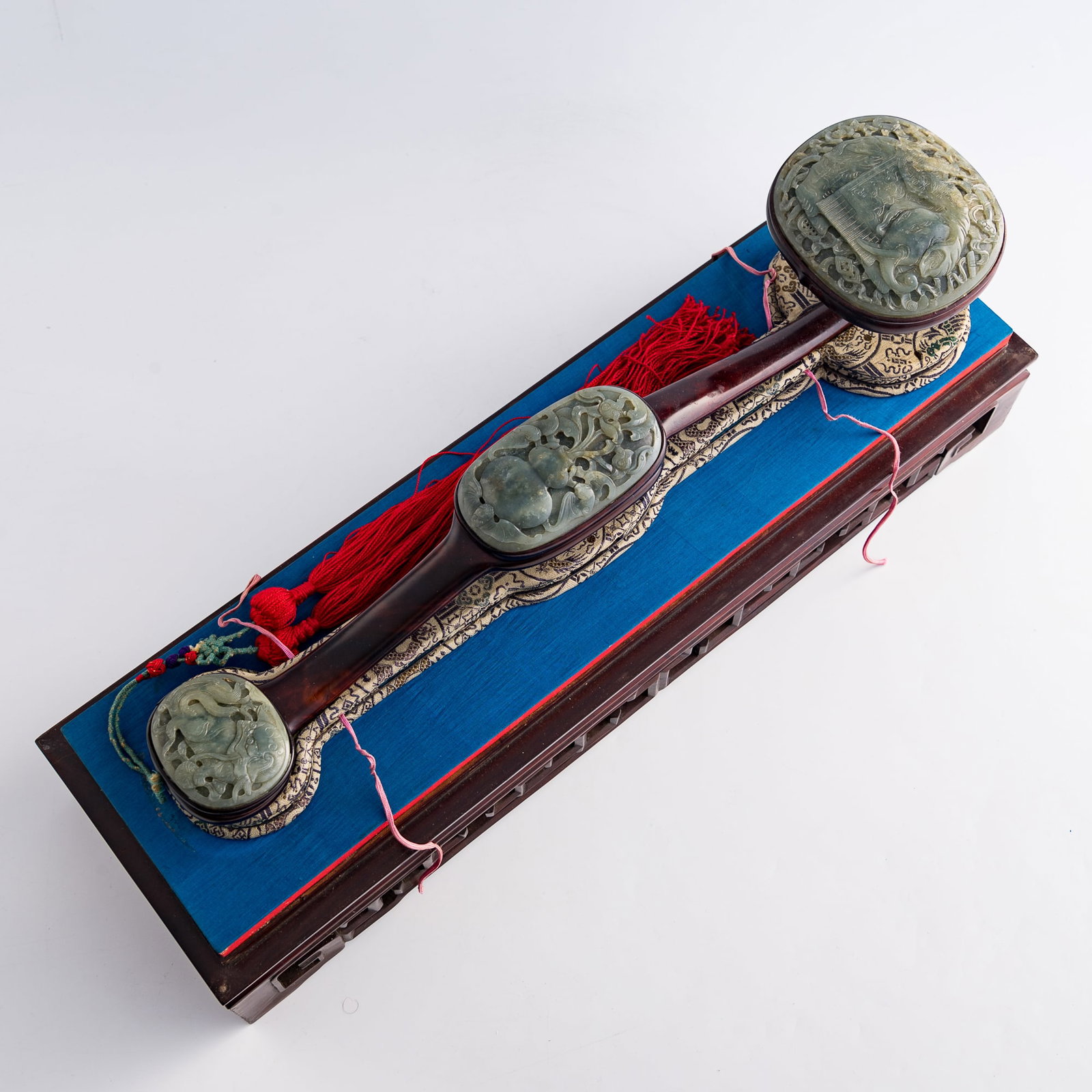 A Chinese hardwood ruyi scepter with three jade mounts, Qianlong period, Qing dynasty: A Chinese hardwood ruyi scepter with three jade mounts Qianlong period, Qing dynasty The largest jade mount is carved with an elephant amid auspicious emblems and scrolling foliage; the medium example