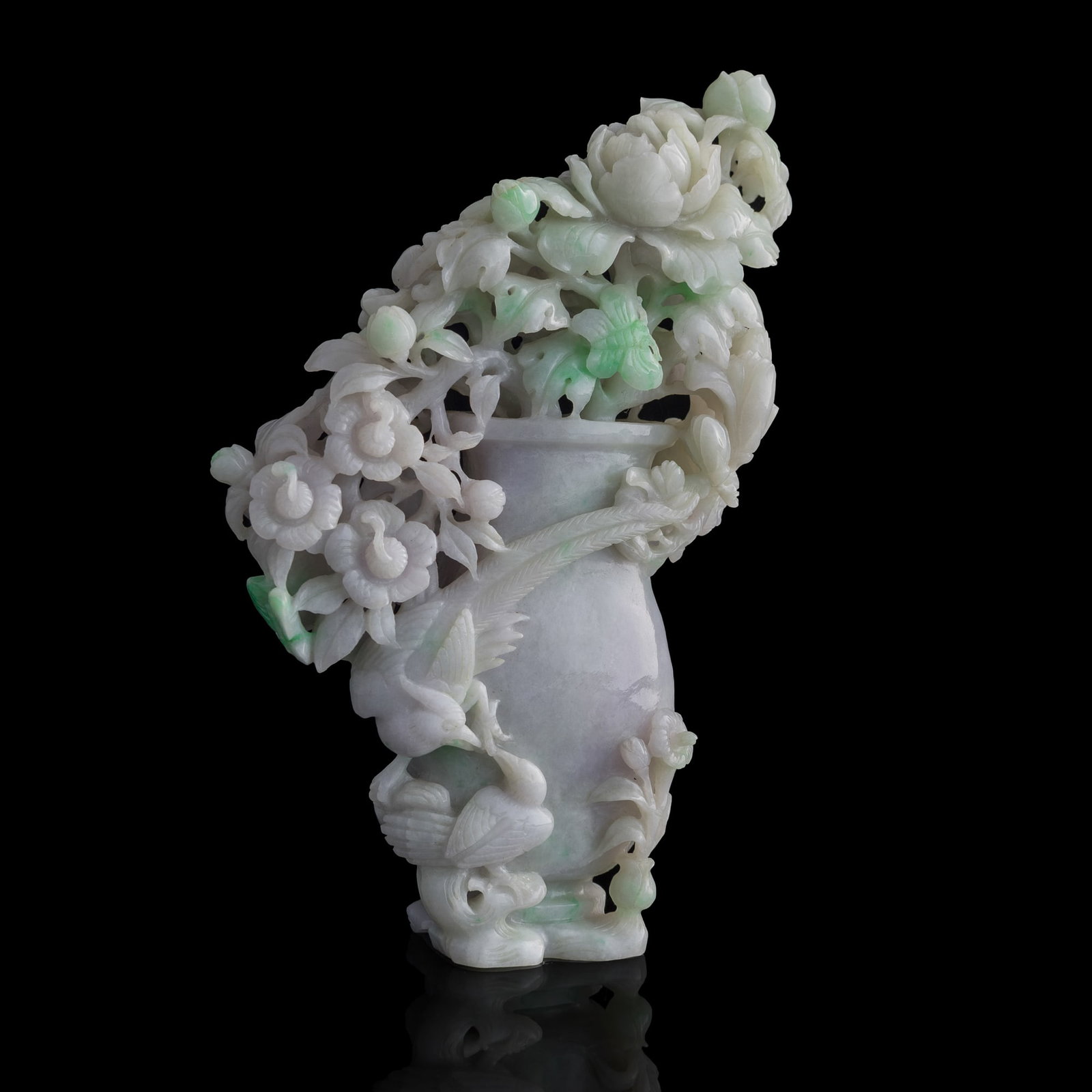 A Chinese jadeite vase with flowers: A Chinese jadeite vase with flowers Carving displays a vase overflowing with flowers, likely peonies, which symbolize wealth, honor, and prosperity. There are also two phoenixes on one side of the vas