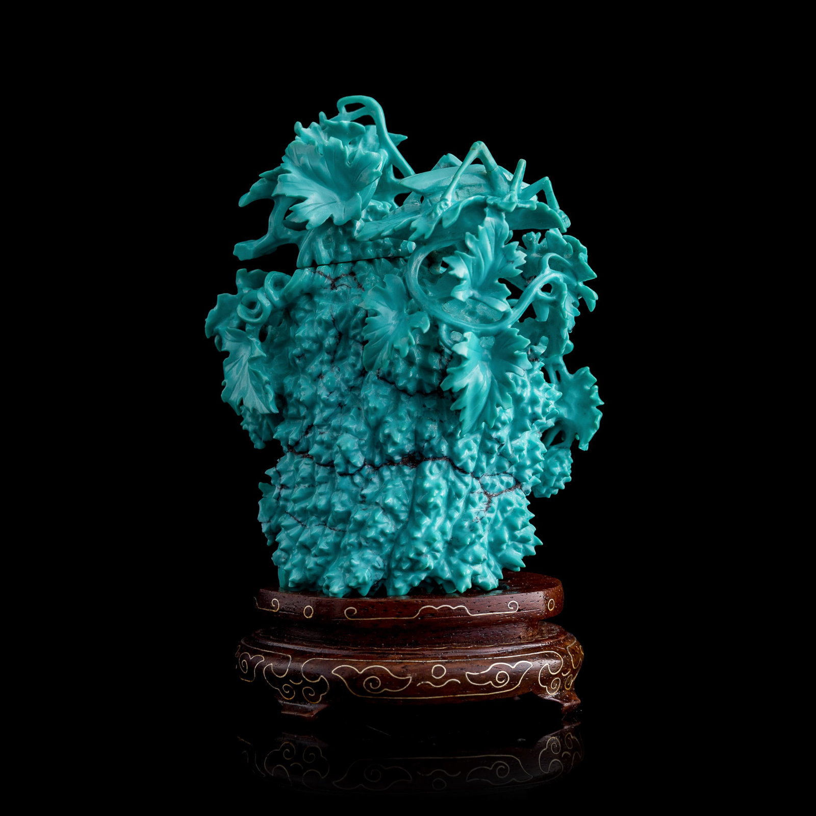 A Chinese carved turquoise 'floral' and 'grasshopper' covered vase, 1960s-1970s: A Chinese carved turquoise 'floral' and 'grasshopper' covered vase 1960s-1970s Sold with associated wooden stand. H: 3 3/8, W: 2 3/4, D: 2 in. (H: 8.6, W: 7, D: 5.1 cm. (turquoise)) Weight: 157 g From