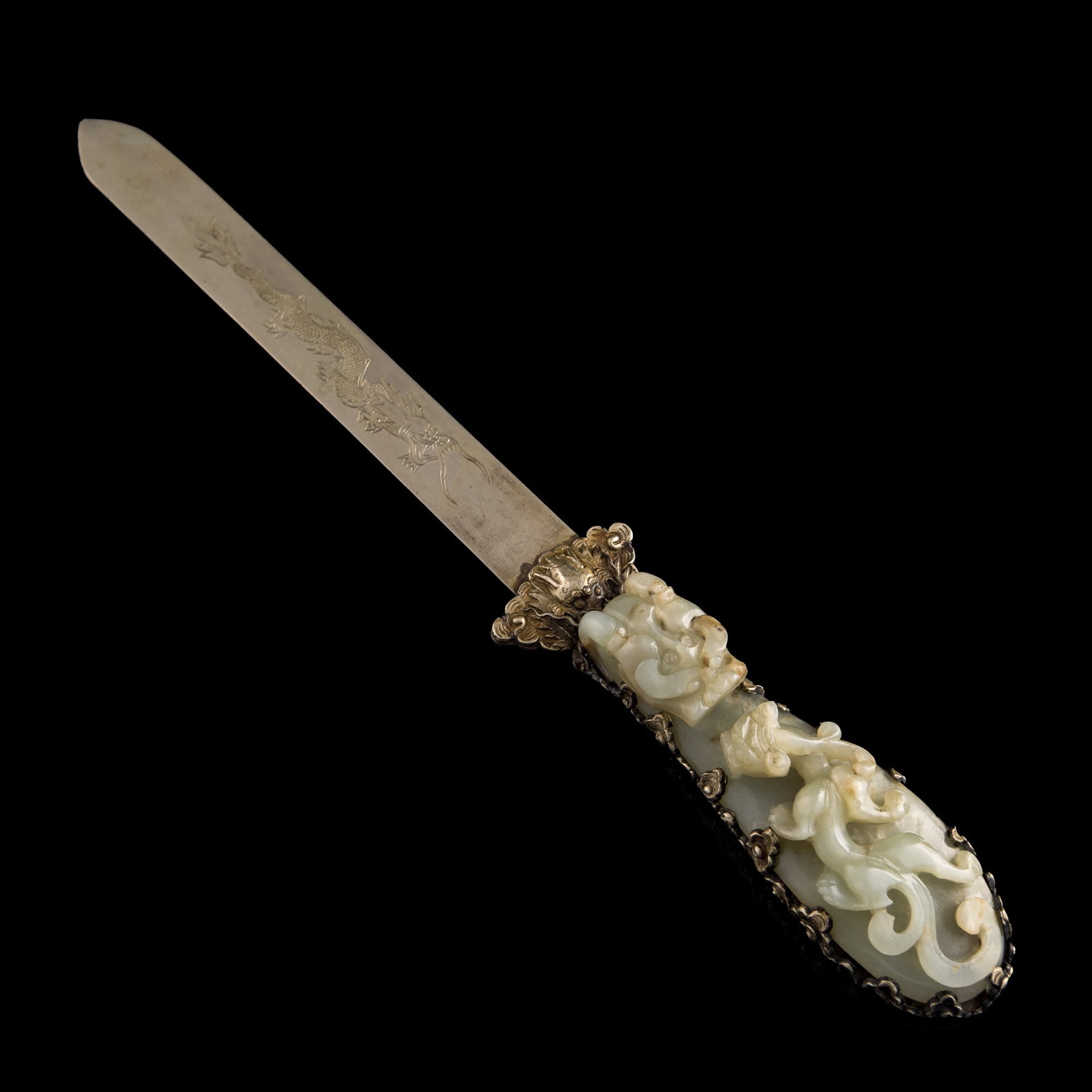 A Chinese silver paper knife with white jade belt-hook handle, 18th century: A Chinese silver paper knife with white jade belt-hook handle 18th century Jade carved in 'chilong' motif; metal to back of handle with four-clawed dragon motif. With 'China' mark to heel of knife. H: