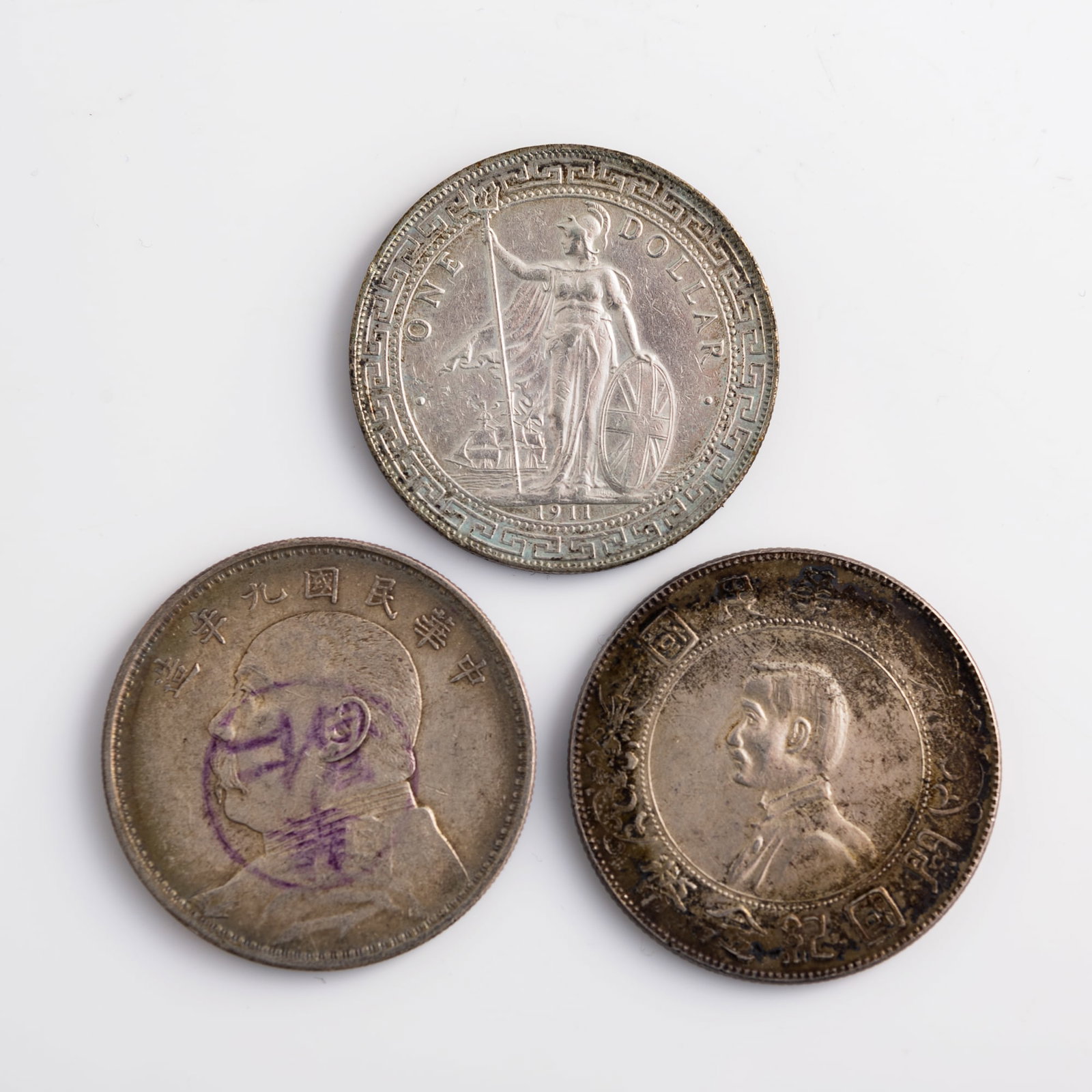 Three Chinese silver coins, Qing dynasty and Republic period: Three Chinese silver coins Qing dynasty and Republic period Comprising a 1911 British Trade Dollar coin; a 'Founding of the Republic' commemorative dollar coin; and a 1920 Yuan Shikai Dollar coin. (3)