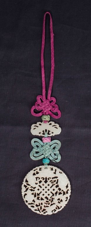 A pierced jade pendant 19th century: A pierced jade pendant 19th century a round white jade pendant carved and pierced with Buddhist symbols along with a small jade carved and pierced pendant connected by strings the round jade pendant i