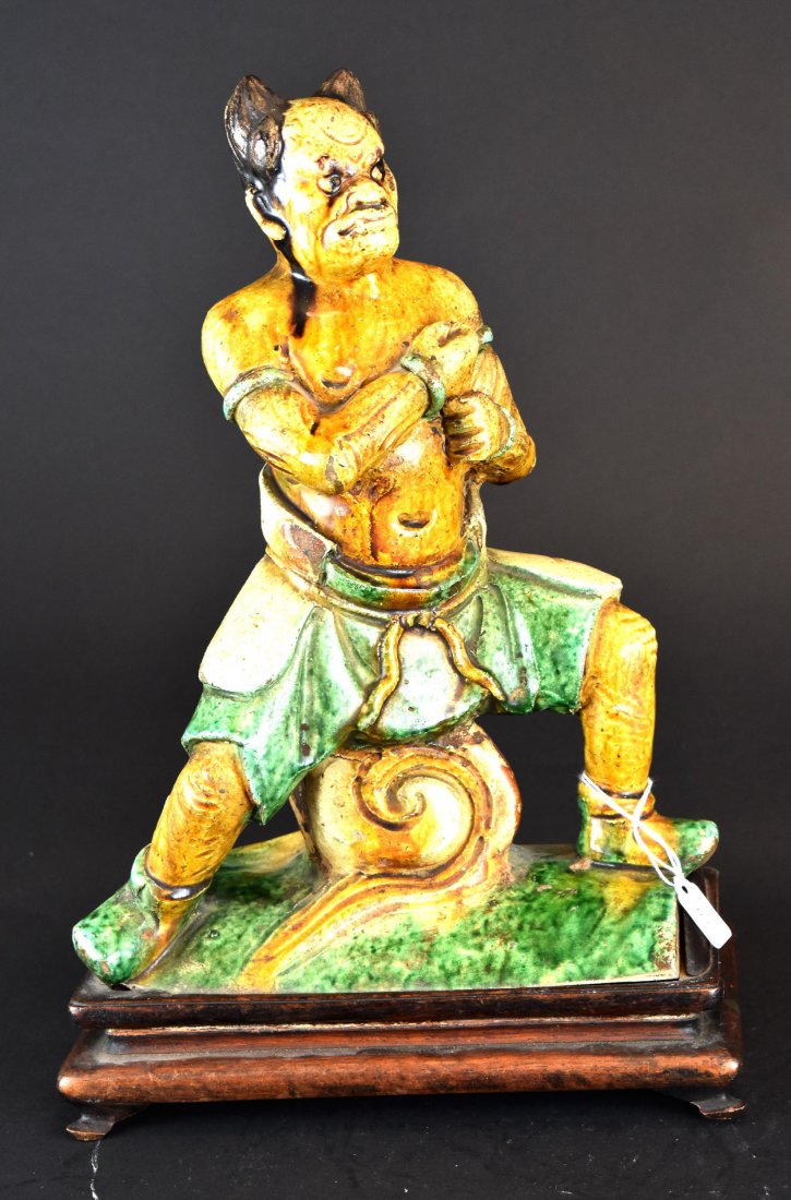 A Sancai Demon Roof Tile, Ming Dynasty: A Chinese Sancai Demon Roof Title, Ming Dynasty (1368-1644) This sancai roof tile features a demon figure. The demon has horns and a fearsome face. He is in a defensive posture astride a cloud swirl w