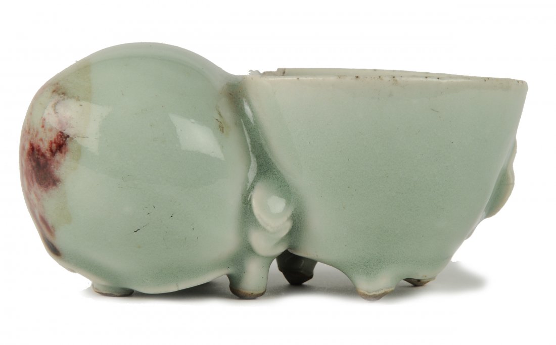 Celadon Peach Shaped Brush Washer, 18th Century: A Chinese Celadon Peach Shaped Brush Washer, 18th Century This celadon colored peach shaped brush washer has an underglaze of copper red. It features details of stems and leaves. It sits upon six smal