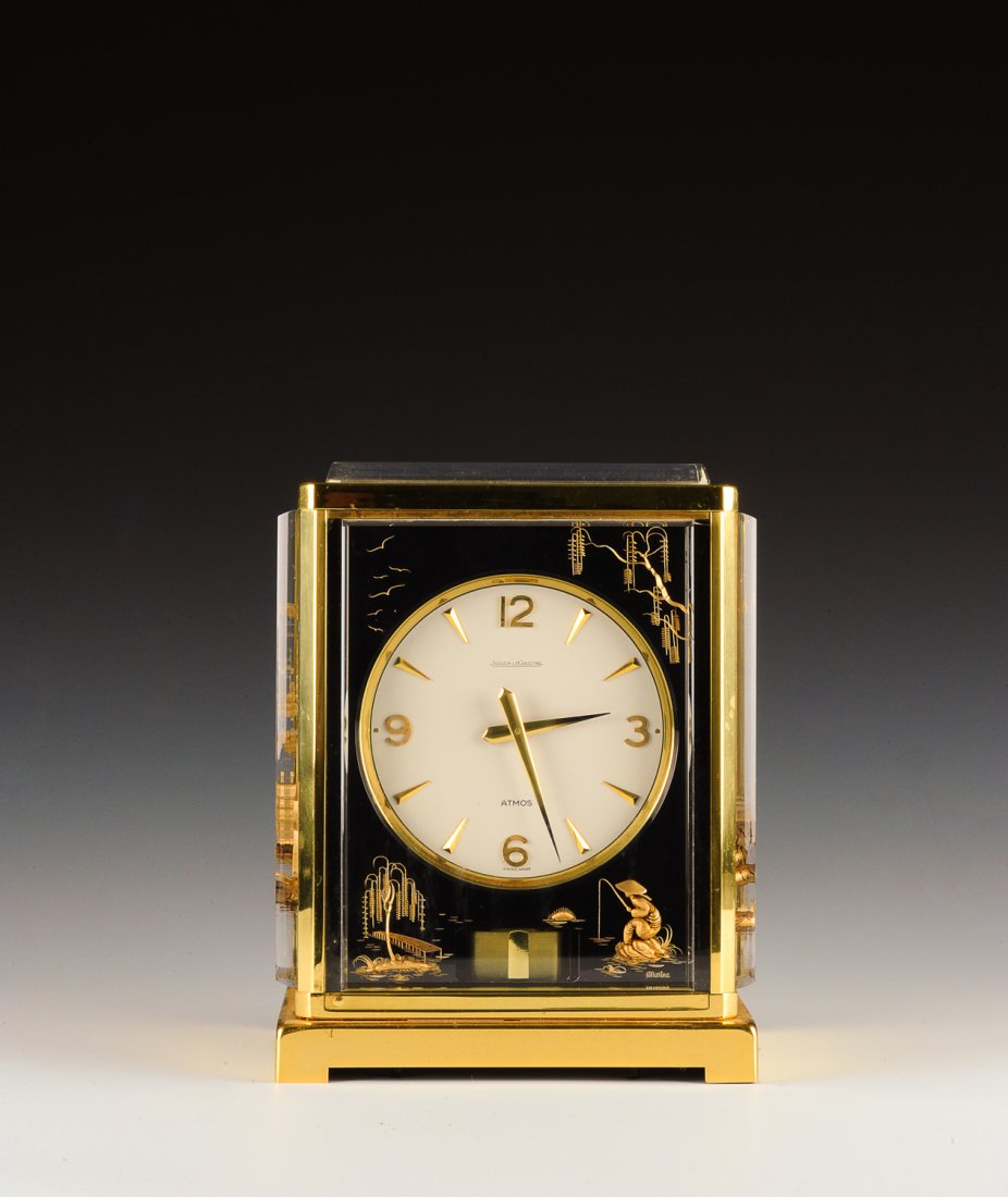 'Marina', Brass Jaeger-LeCoultre Atmos Swiss Clock: This elegant perpetual motion clock is Swiss made by Jaeger-LeCoultre. It is part of their Atmos line and titled 'Marina'. The clock has a brass and Lucite frame. The decorative black panels with thre