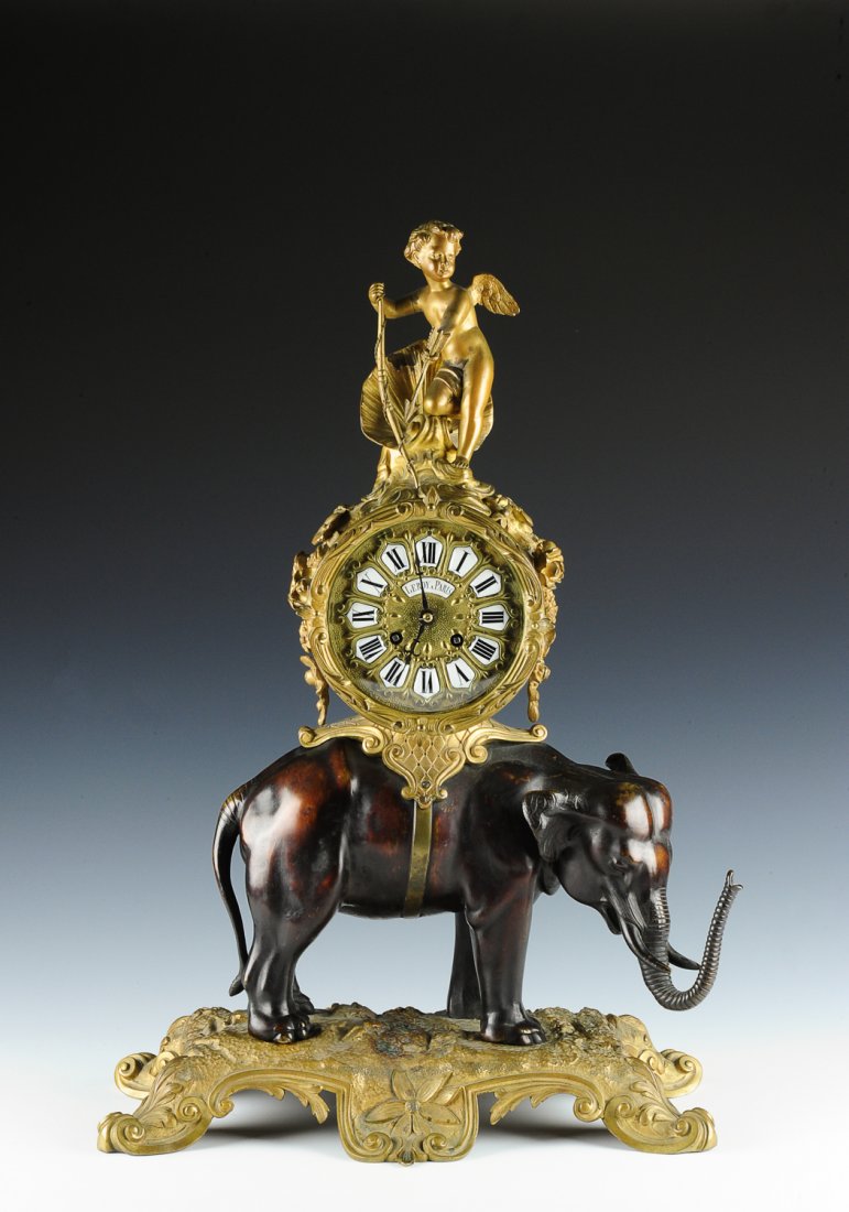 LeRoy Elephant & Cupid Ormolu Clock, France: This Ormolu elephant and cupid clock is labeled "LeRoy a Paris" on the face. The clock dates to the 19th Century. The base and elephant are bronze. The dial has enameled Roman Numerals with decorative