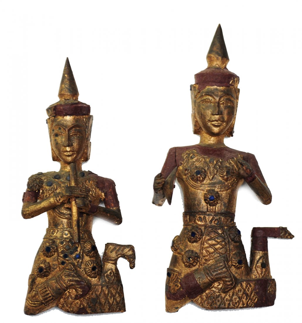 Pair of Wooden Thai Buddhas: These two wooden Buddha's are painted golden, one holds a flute and the other, cymbals. They are adorned with pieces of blue glass and have hooks for hanging. The larger figure is 12"; the smaller is 