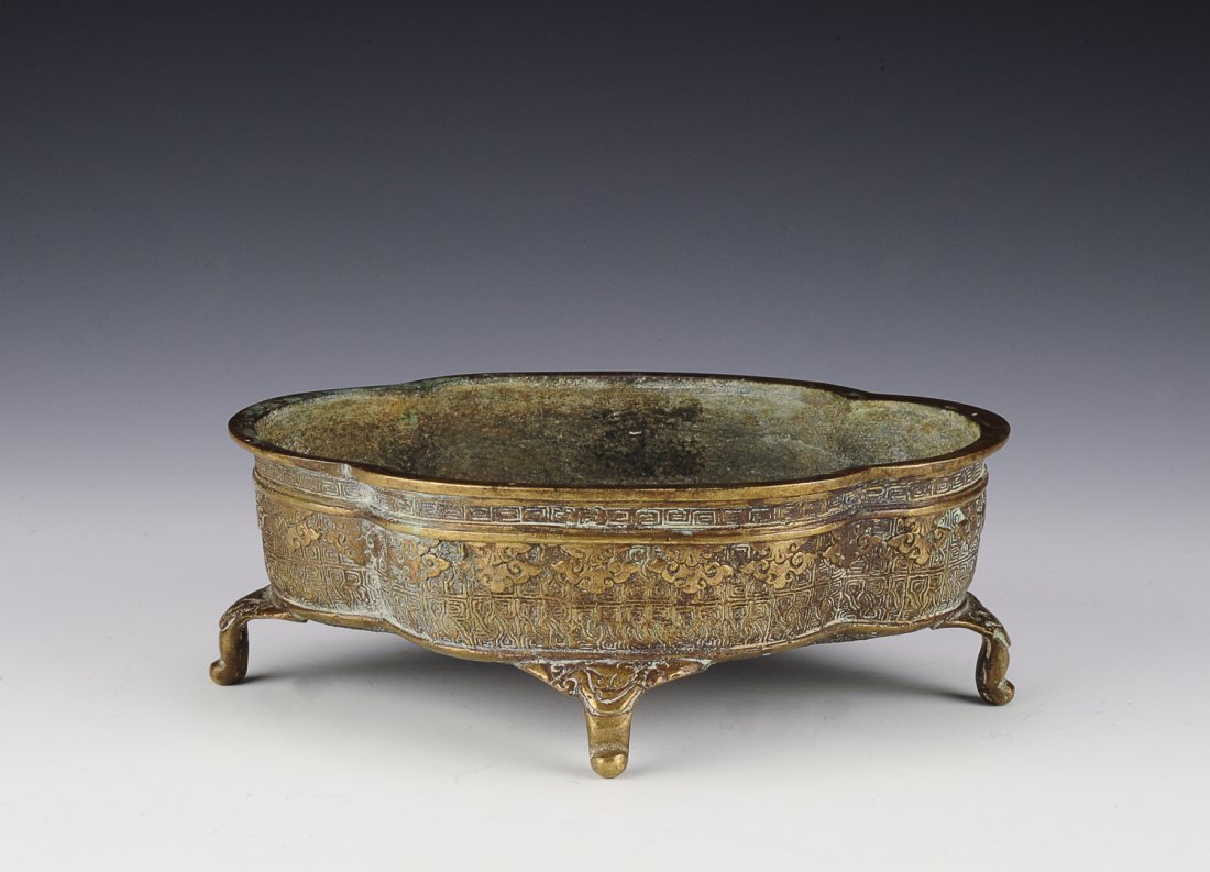 Bronze Incense Burner: This incense burner has geometric patterns covering the its exterior along with a lingzhi border and a Greek key design circling underneath the rim. It sits atop four feet. The bottom has a three-char