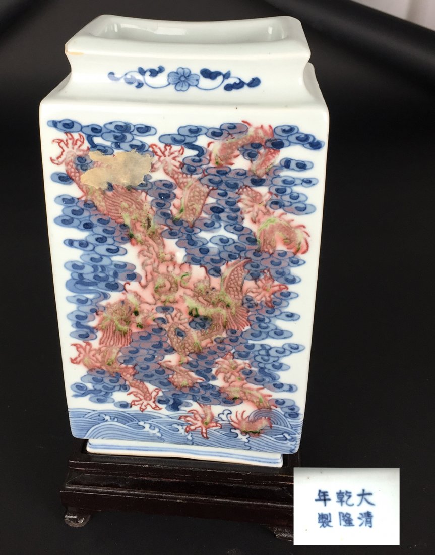 Red & Blue Underglaze Square Vase, 20th Century: This square white glazed vase has a red, blue, and green underglaze of dragons and clouds over waves. On the bottom is a 6 character mark in blue under glaze. Included is a decorative wooden stand. Di