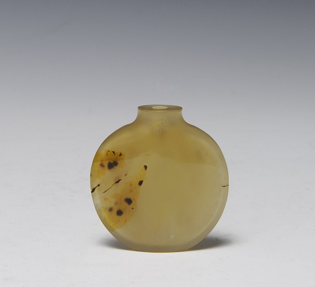 Round Agate Snuff Bottle, 19th Century: Round agate snuff bottle from the 19th century. The bottle is a light beige color with some darker spots. It has no spoon or stopper. Dimensions are 21/8 inches wide by 2 1/8 inches high. All measurem