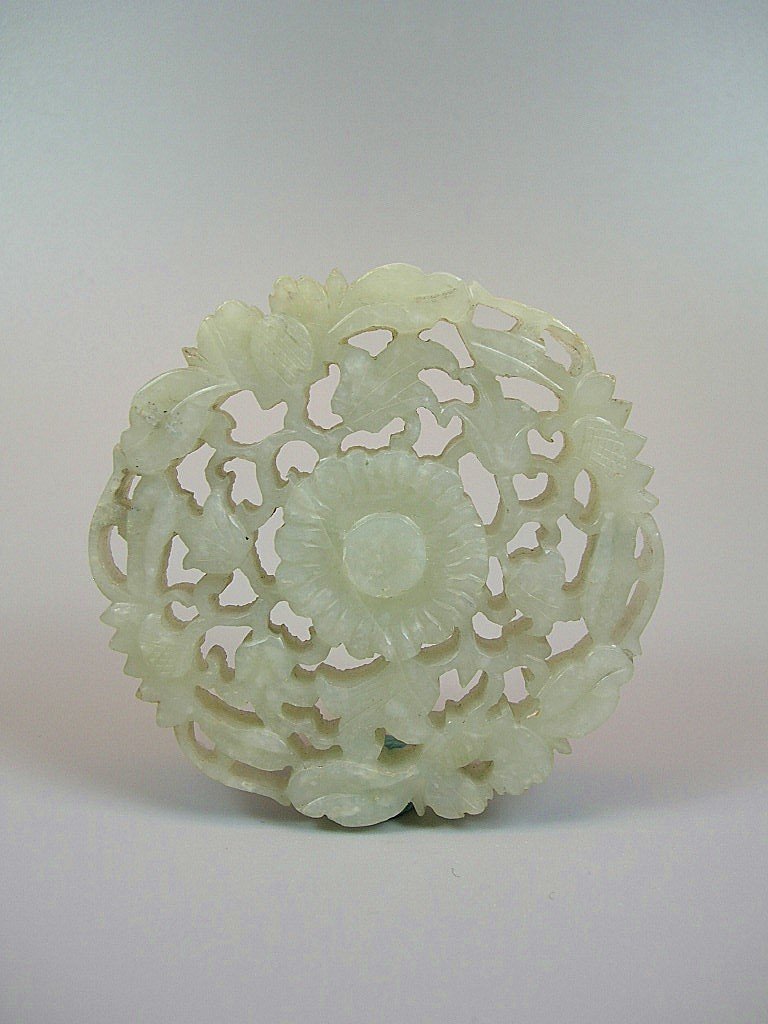 Ming Dynasty Carved Pale Celadon Jade Roundal: Decorated with openwork of floral patterns, Ming Dynasty, good condition, some natural fissures, age wear, 2 5/8" (6.7 cm) diam.