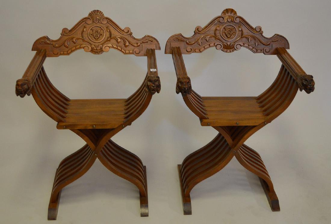 Two (2) carved mahogany continental campaign-style: Two (2) carved mahogany continental campaign-style folding chairs. Lion heads on arms, carved folate flourishes on removable back. 36” height, depth 21”, 26” width, seat height 19.5”