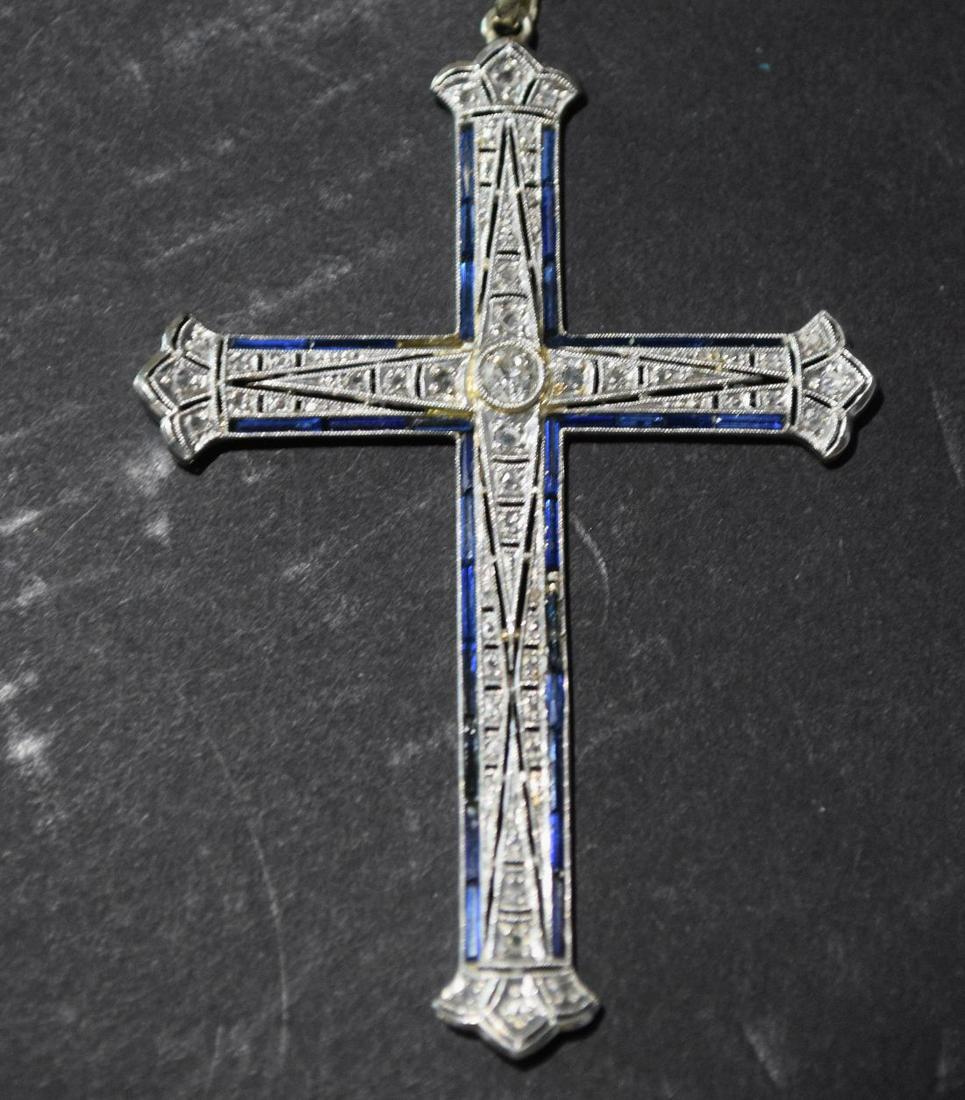 18K White Gold Diamond Sapphire Cross Pendant. 2.5": 18K White Gold Diamond Sapphire Cross Pendant. 2.5" Long weight 5.8 grams Center diamond is .20 with smaller diamond chips outlined in Sapphire