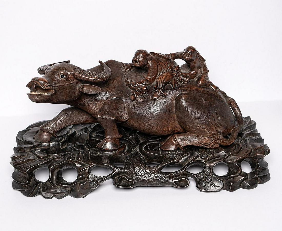 EARLY JAPANESE CARVED WOOD WATER BUFFALO with children: EARLY JAPANESE CARVED WOOD WATER BUFFALO with children riding on it's back. The Buffalo with glass eyes sits on a custom carved wood base. Condition: the piece has two age cracks and one repair to the