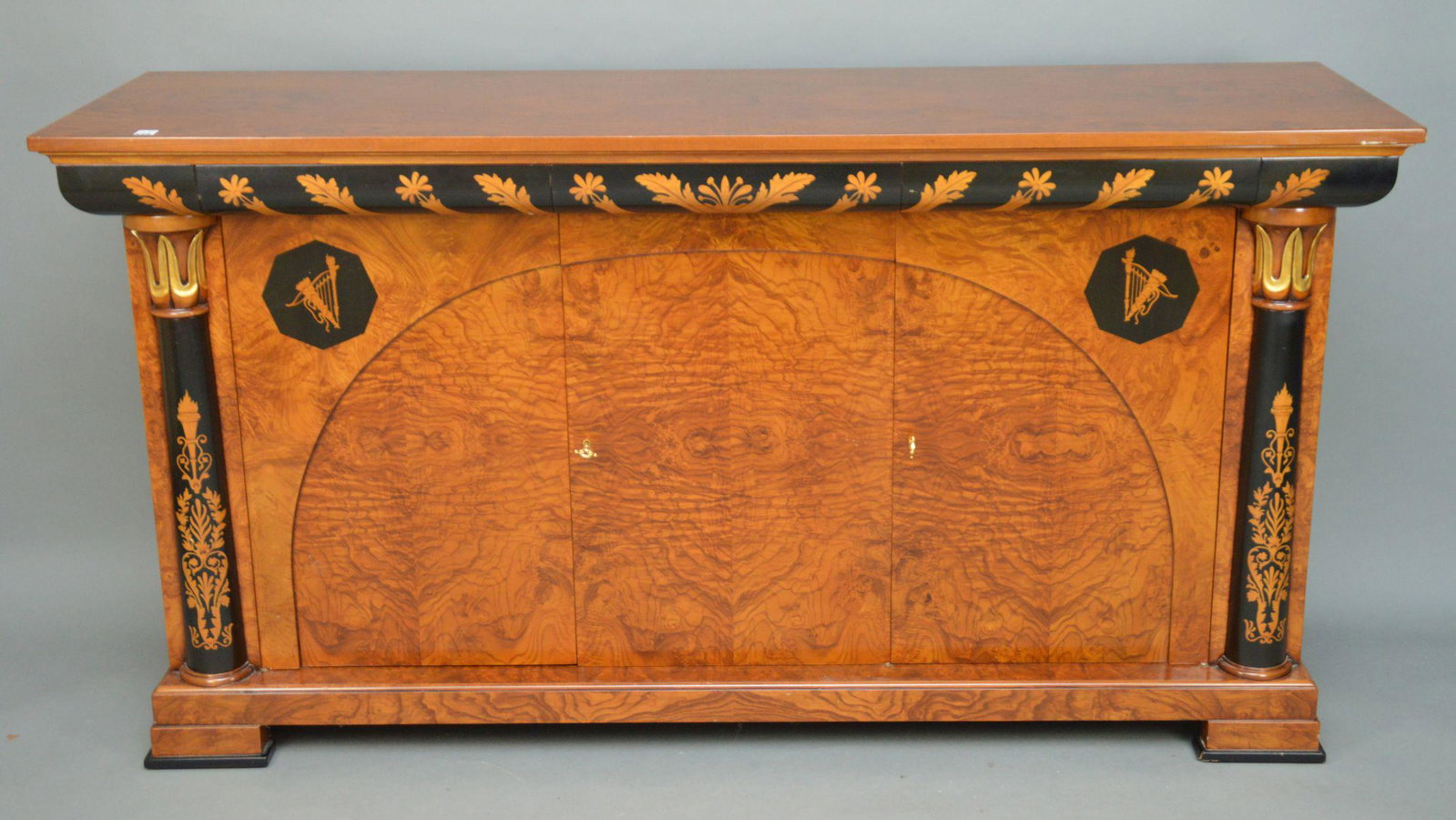 BURLWOOD INLAID CARVED AND GILDED SIDEBOARD. The piece: BURLWOOD INLAID CARVED AND GILDED SIDEBOARD. The piece with inlaid torch, foliate and ebonized decoration. The piece with three original bronze keys. Condition: good with no damage identified. Height 