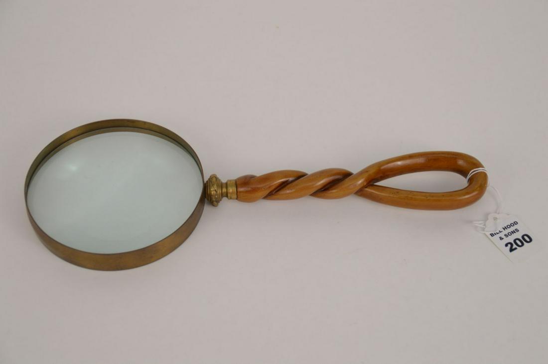 LARGE HANDHELD MAGNIFYING GLASS WITH CARVED BONE HANDLE: LARGE HANDHELD MAGNIFYING GLASS WITH CARVED BONE HANDLE - Bronze fittings around 4 7/8” diameter glass. Carved and stained twisted bone handle. 13 1/4” L. Condition: Minor normal wear.