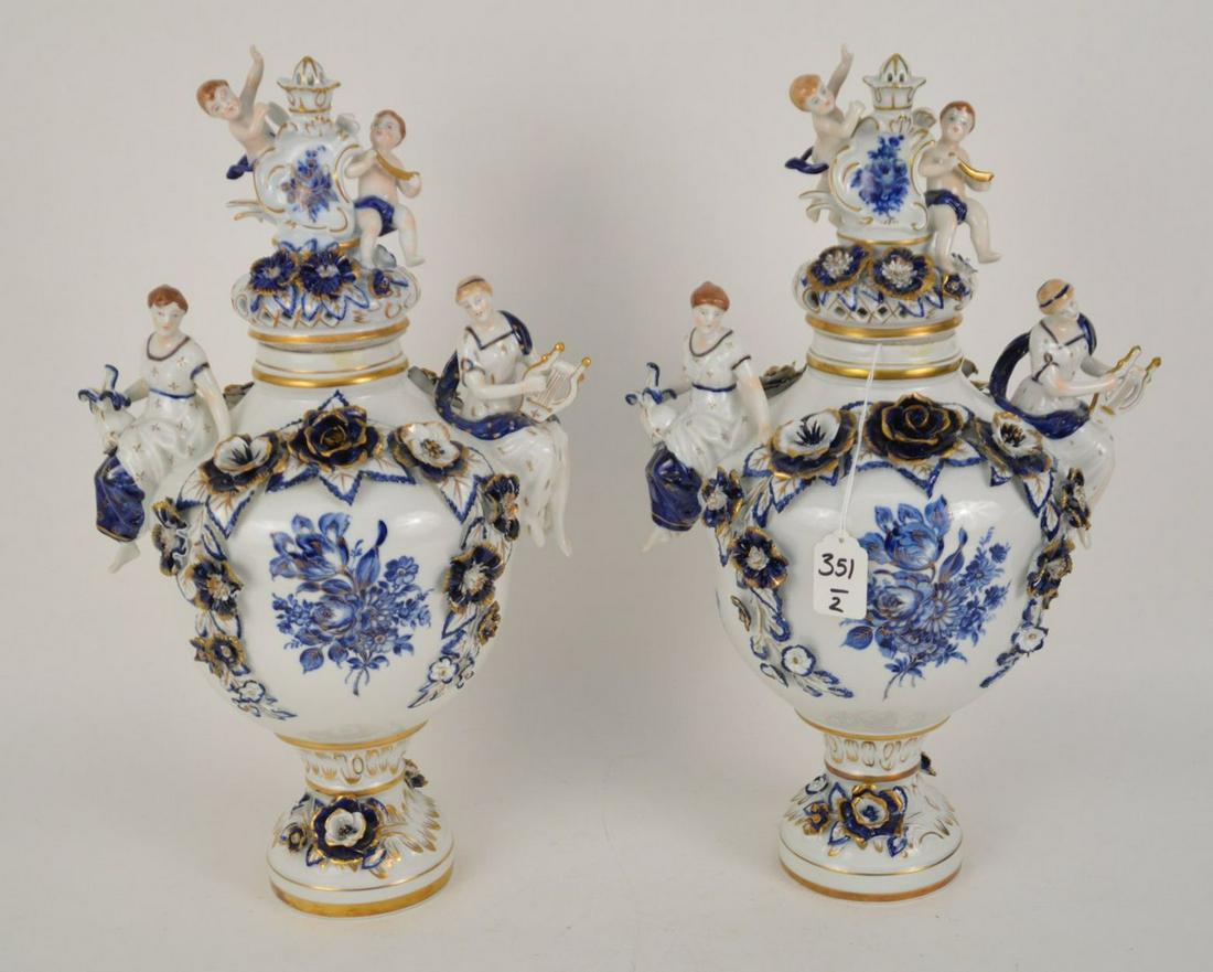 PAIR OF UNMARKED MEISSEN-STYLE COVERED URNS - 20th: PAIR OF UNMARKED MEISSEN-STYLE COVERED URNS - 20th century. Porcelain urns with female muses at each side and puttis on lid. Having blue & white decoration with gilt accents. 18 1/2" H. Condition: a f