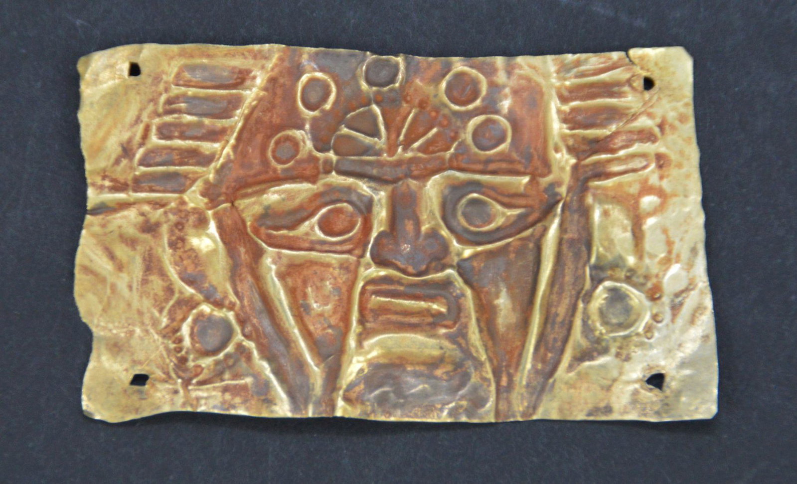 Pre-Columbian Sinu Gold Relief Pectoral, Detailed: Pre-Columbian Sinu Gold Relief Pectoral, Detailed Relief Pectoral of Warrior, Traces of Cinnabar, Holes for Suspension, High Karat Gold 20-22, 3 Grams, 1 1/2" x 2 1/2". Origin: Colombia, Age:800-1200 