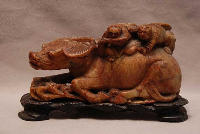 Carved soapstone animal with 2 figures a top on wo: Carved soapstone animal with 2 figures a top on wood stand, 6"w x 3"h