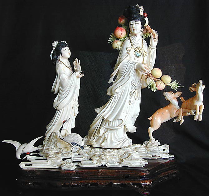 VINTAGE CHINESE POLYCHROME IVORY GROUPING A finely: VINTAGE CHINESE POLYCHROME IVORY GROUPING A finely carved and polychrome grouping of a royal woman holding twigs of peaches with her maid servant carrying a teapot and tray; mounted to the ivory groun
