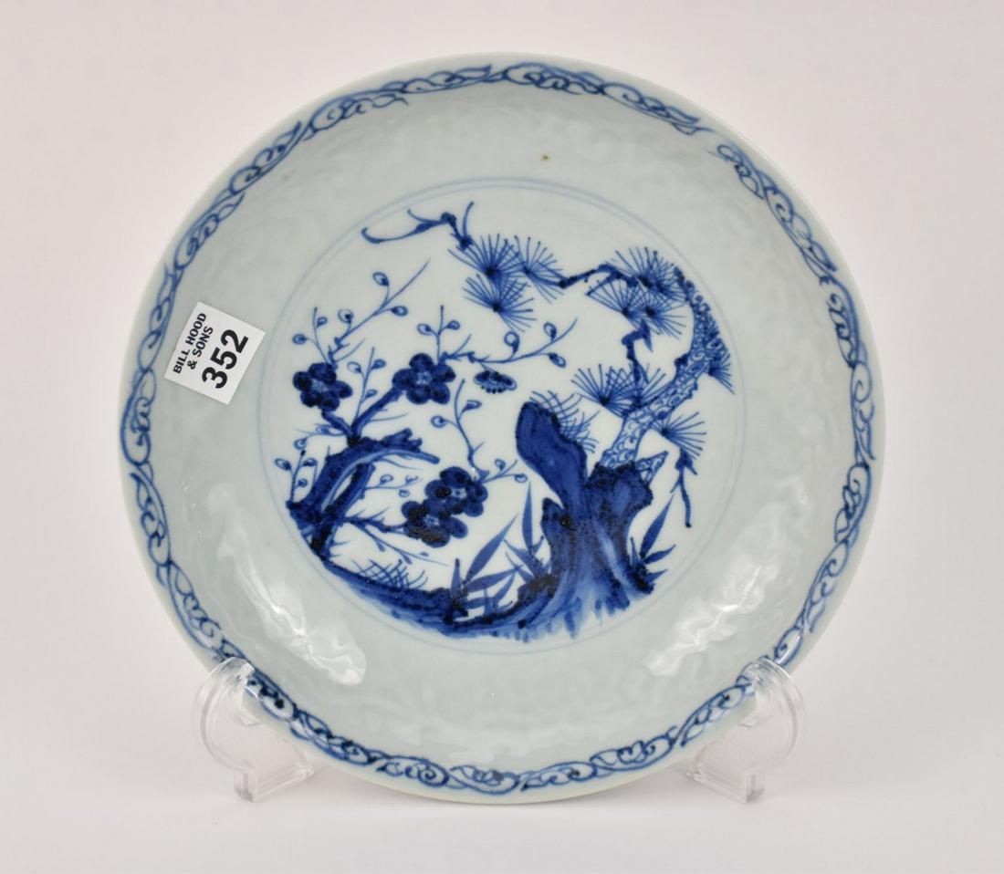 Chinese Blue & White Porcelain Plate - A shallow bowl with a foliate scene in blue underglaze with a: Chinese Blue & White Porcelain Plate - A shallow bowl with a foliate scene in blue underglaze with a blueish-white ground. The walls of the bowl have a scroll pattern in relief. Unglazed underside. Pr