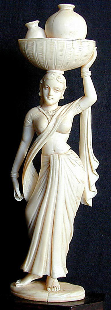 OLD IVORY CARVING OF VOLUPTUOUS HINDU WOMAN An old: OLD IVORY CARVING OF VOLUPTUOUS HINDU WOMAN An old ivory carving of a voluptuous Hindu woman carrying a basket full of jugs atop her head, mounted on a carved rosewood base, total height with base 8.2