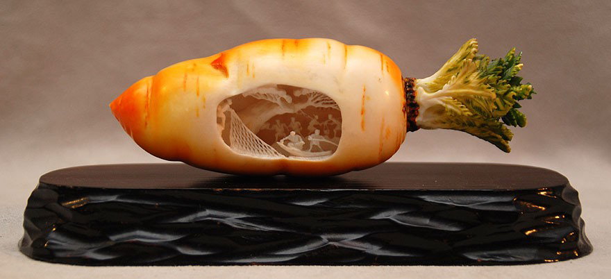CHINESE POLYCHROME IVORY CARROT W/ INTERIOR SCENE: CHINESE POLYCHROME IVORY CARROT W/ INTERIOR SCENE, An intricately carved and polychrome Chinese ivory figure of an orange carrot with a deeply carved 3 dimensional interior scene depicting fishermen w