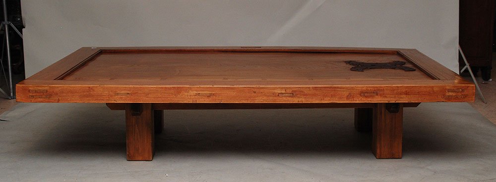 Wood coffee table formed from a Japanese door, mou: Wood coffee table formed from a Japanese door, mounted with large wrought iron escutcheon at one end, custom base, 45"w x 73"L
