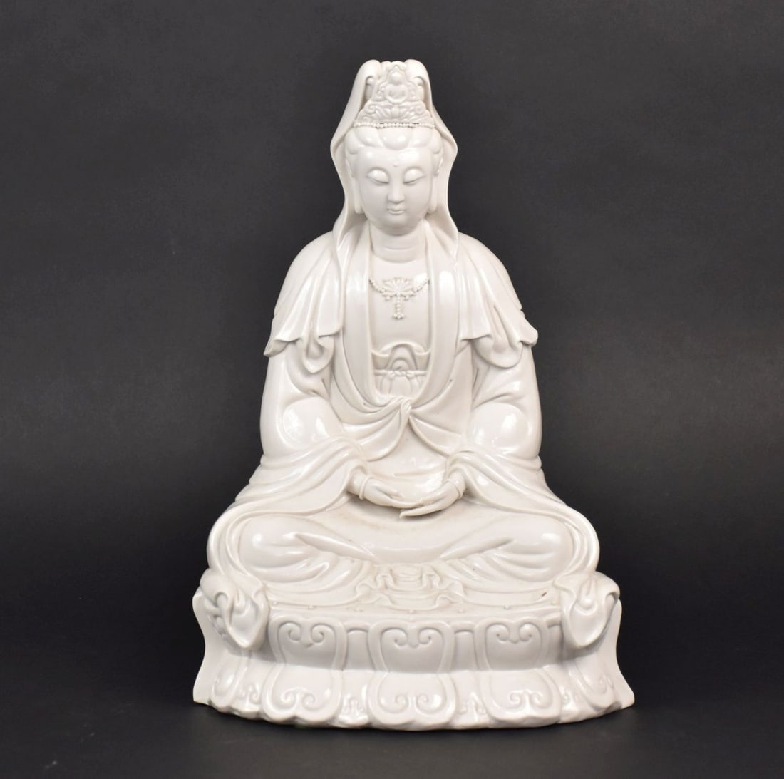 Blanc de Chine Porcelain Figure of Guanyin - White glazed porcelain figure of Kuan Yin seated in a: Blanc de Chine Porcelain Figure of Guanyin - White glazed porcelain figure of Kuan Yin seated in a meditative pose. 15 3/4" h x 10" w. Condition: No damage identified.