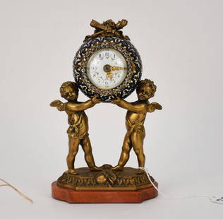 Antique French Gilt Bronze Enamel Putti Clock - Late 19th-Early-20th century. A small boudoir clock: Antique French Gilt Bronze Enamel Putti Clock - Late 19th-Early-20th century. A small boudoir clock featuring two gilt bronze cherubs/putti holding up the enamel decorated clock, surmounted by a bronz