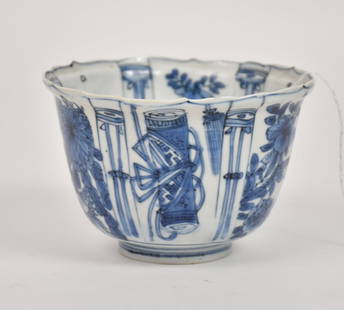 Blue And White Porcelain Bowl, Wanli Period - Ming Dynasty, China. A deep porcelain tea bowl with: Blue And White Porcelain Bowl, Wanli Period - Ming Dynasty, China. A deep porcelain tea bowl with scalloped lotus petal flared rim. Blue underglaze decoration depicting florals and sacred objects, a p