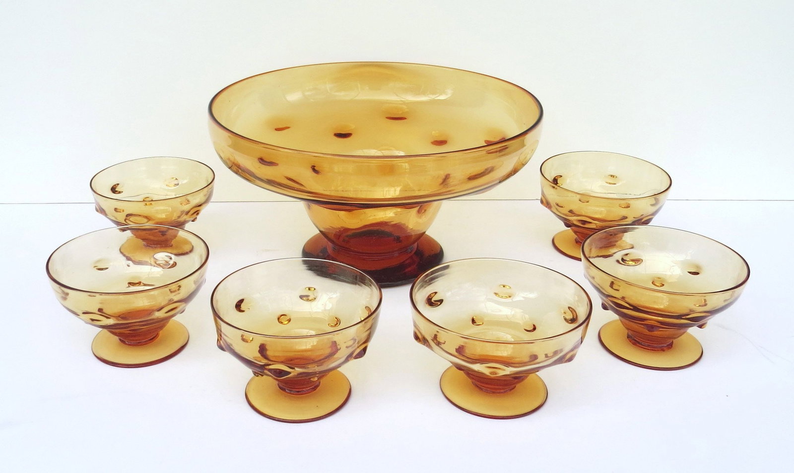 Unusual WEBB Art Nouveau seven-piece Dessert Set, comprising large footed Center Bowl, with six: Unusual WEBB Art Nouveau seven-piece Dessert Set, comprising large footed Center Bowl, with six individual Footed Bowls. All hand blown of rich Amber lead glass with raised, knobby prunts around sides