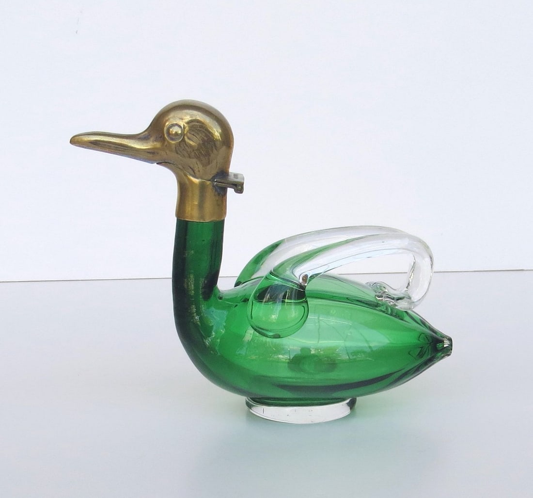 Antique AUSTRIAN BIRD FORM DECANTER; hand blown of Emerald Green glass with two applied clear: Antique AUSTRIAN BIRD FORM DECANTER; hand blown of Emerald Green glass with two applied clear handles and a Brass HEAD-FORM spout (marked AUSTRIA). Arts and Crafts style, circa 1900; 5 ¾ inches