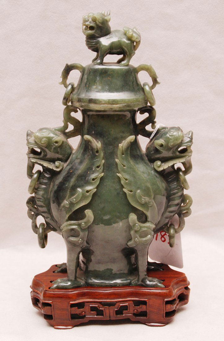 Spinach green jade bronze form vase and cover on fitted: Spinach green jade bronze form vase and cover on fitted wood stand, Dog of Fo Finial, finely carved with Ch'ilin heads, winged body and feet, loose rings on heads, the Dogs of Fo were known as the gua
