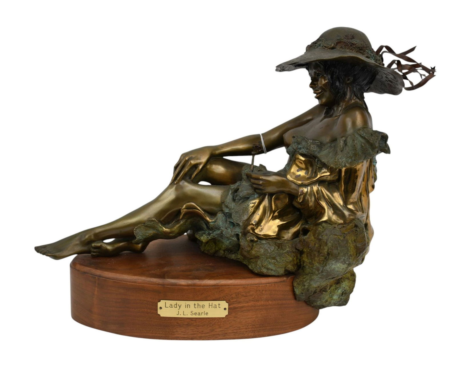 J.L Searle "The Lady in the Hat" Bronze - Patinated and gilt bronze sculpture depicting a young: J.L Searle "The Lady in the Hat" Bronze - Patinated and gilt bronze sculpture depicting a young semi-nude lady reclining in a hat. Wood base with title plaque. 13 1/2" h x 16" l.