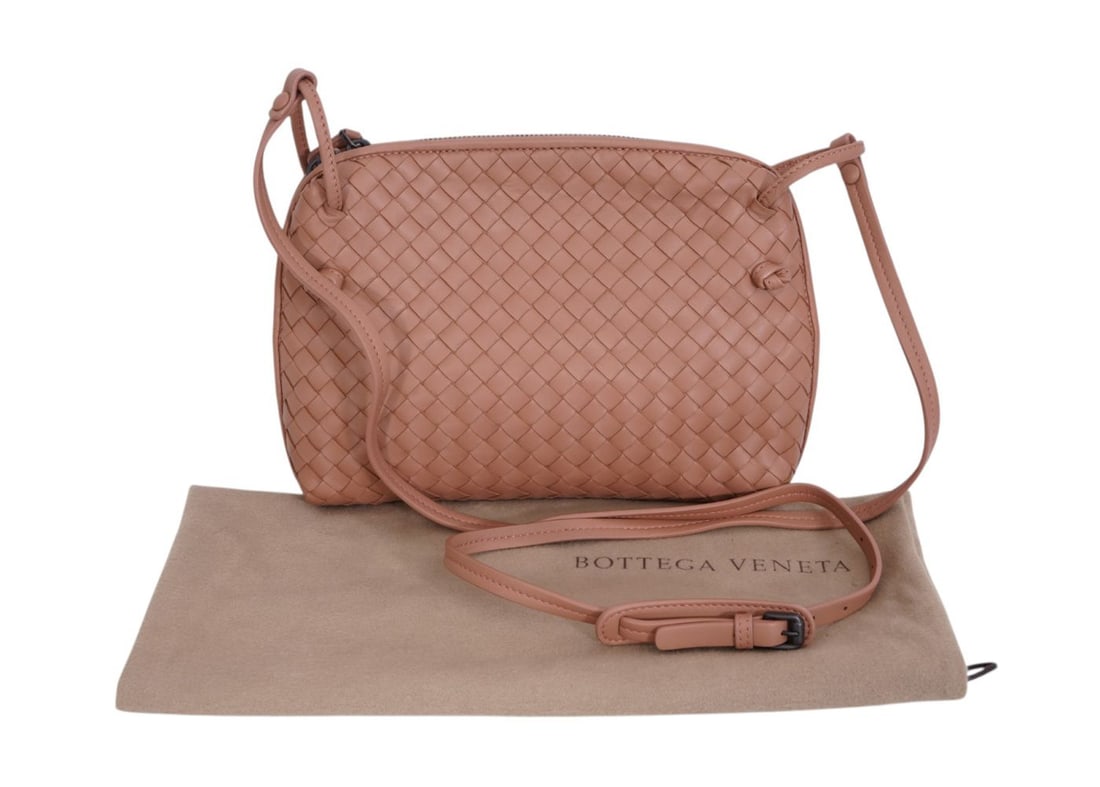 Bottega Veneta Dusty Rose Crossbody featuring the signature Intrecciato woven design with a long: Bottega Veneta Dusty Rose Crossbody featuring the signature Intrecciato woven design with a long adjustable slim crossbody strap. Made of exceptionally soft Nappa lambskin. Dual zip top closure. Bag h