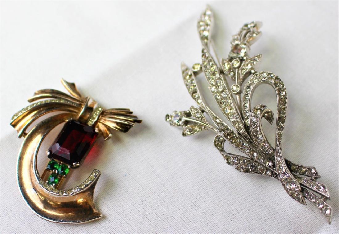PAIR OF SIGNED TRIFARI COSTUME JEWELRY: To include a signed Trifari Philippe rhinestone spray pin and a Trifari red stone fur clip. Shipping to be $15 US. We will combine w/ price.