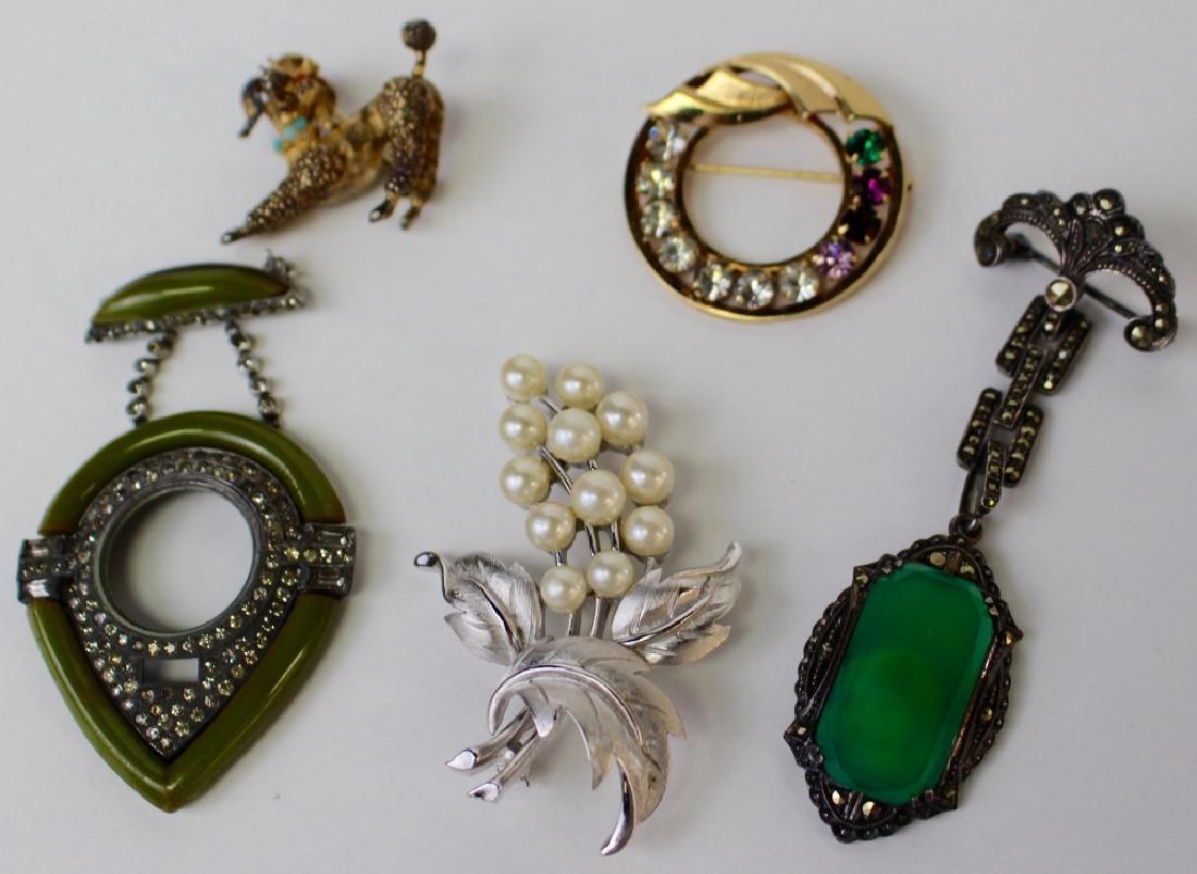 LOT OF SIGNED & UNSIGNED COSTUME PINS: To include a Deco dangle pin, a gold filled rhinestone circle pin, a poodle scottie pin, a marcasite w/ green stone dangle pin, and a Trifari Philippe faux pearl pin. Shipping to be $15 US. We will co