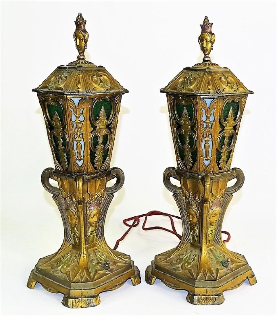ANTIQUE ORNATE WHITE METAL TABLE LAMPS: Early 20th century white metal table lamps with ornate design, having figural royalty decor and glowing glass inserts. Pair is electrified with single wire. Measures approx. 17-1/2"H. Third party ship