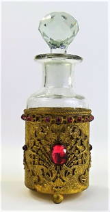 FRENCH PERFUME BOTTLE IN JEWELED BRASS MOUNT: Vintage French crystal perfume bottle, with flared neck and rounded facet cut stopper. Held in a ornate brass mount with floral decorations, set with multiple pink color glass jewels. Measures