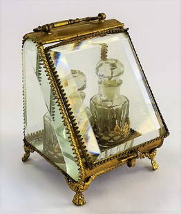 ANTIQUE FRENCH DOUBLE BOTTLE PERFUME CASKET: Antique French perfume bottle casket, containing two bottles. With brass frame withholding the bottles behind four panes of beveled glass. Stands approx. 4"H x 3-1/2"W. Third party shipping is require