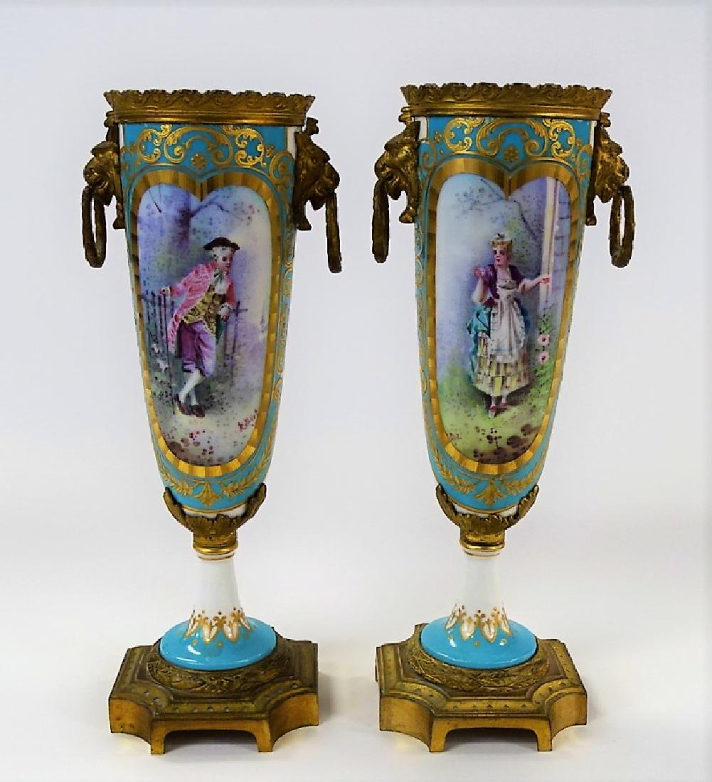 PR FRENCH H/P BRONZE MOUNTED PORCELAIN VASES: Pair of French Sevres style porcelain garniture vases having bronze collars, looped Lion rampart handles, column mount, and squared footed bases. Hand decorated with portrait tableaus bordered in cele