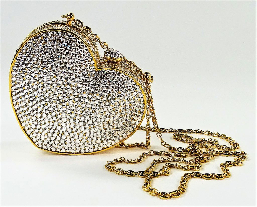 STUART WEITZMAN CRYSTAL JEWELED HEART MINAUDIERE: Stuart Weitzman Crystal jeweled minaudiere purse from The Pavé Collection. In heart shape form, jeweled throughout with hand set Austrian Crystals. Opens to leather lined interior. Has optional 25" o