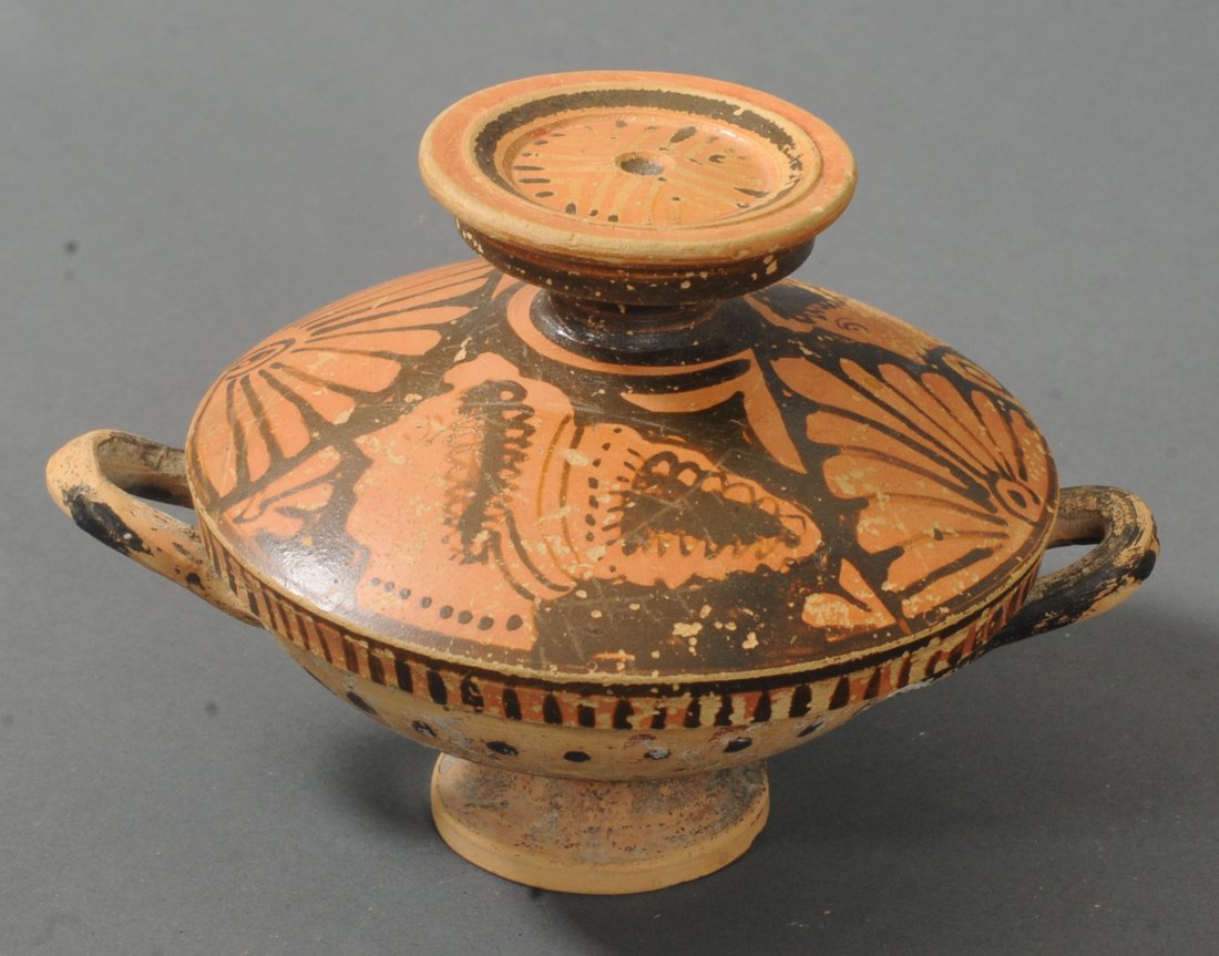 ANCIENT GREEK APULIAN LIDDED LEKANIS: The lid is decorated with two heads of lady of fashion, separated by two palmettes. Circa 3rd century B.C.Measurements: 3 1/2 in. H. (8.9 cm.) 5 in. W. (12.7 cm.)Ex: Virginia private collection; Ex: E