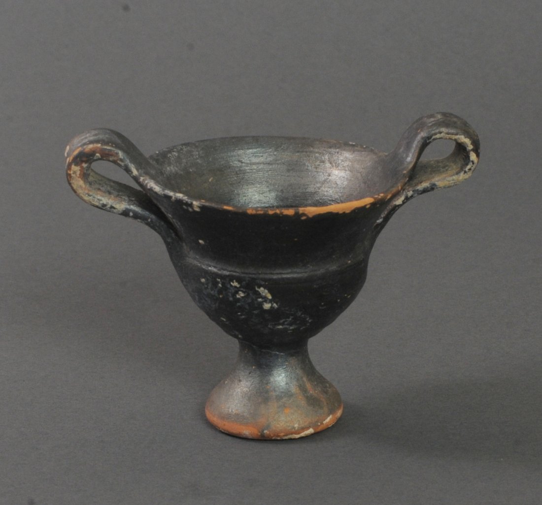 ANCIENT GREEK POTTERY SKYPHOS CUP: Twin handled cup resting on a elevated base. Measurements: 3 in. H. (7.6 cm.) Ex: California private collection, 1980s; Ex: European art market. Reference No. AGA2-105. Authenticity guaranteed. A cert
