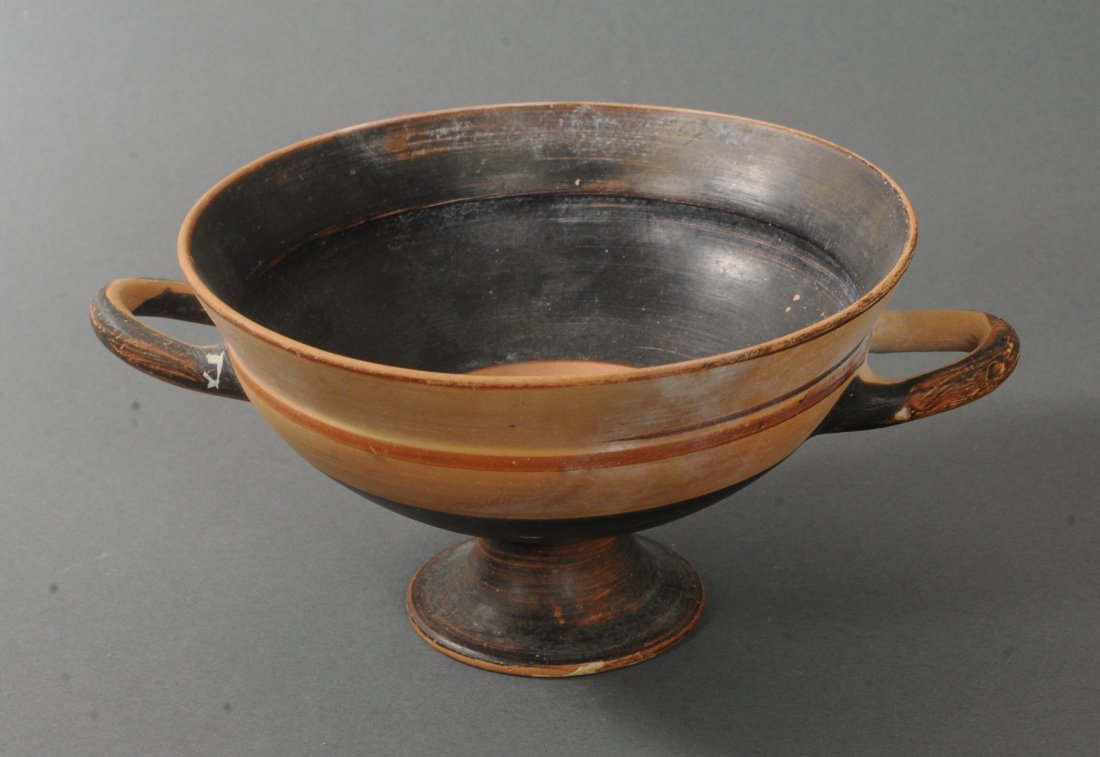 ANCIENT GREEK LARGE FOOTED CUP: With twin handles, standing on a raised, footed base. Circa 500-400 B.C. Measurements: 4 in. H. (10.2 cm.) 8 1/4 in. Diam. (21 cm.) Ex: Important West Coast private collection of glass, 1970's; Ex: Da